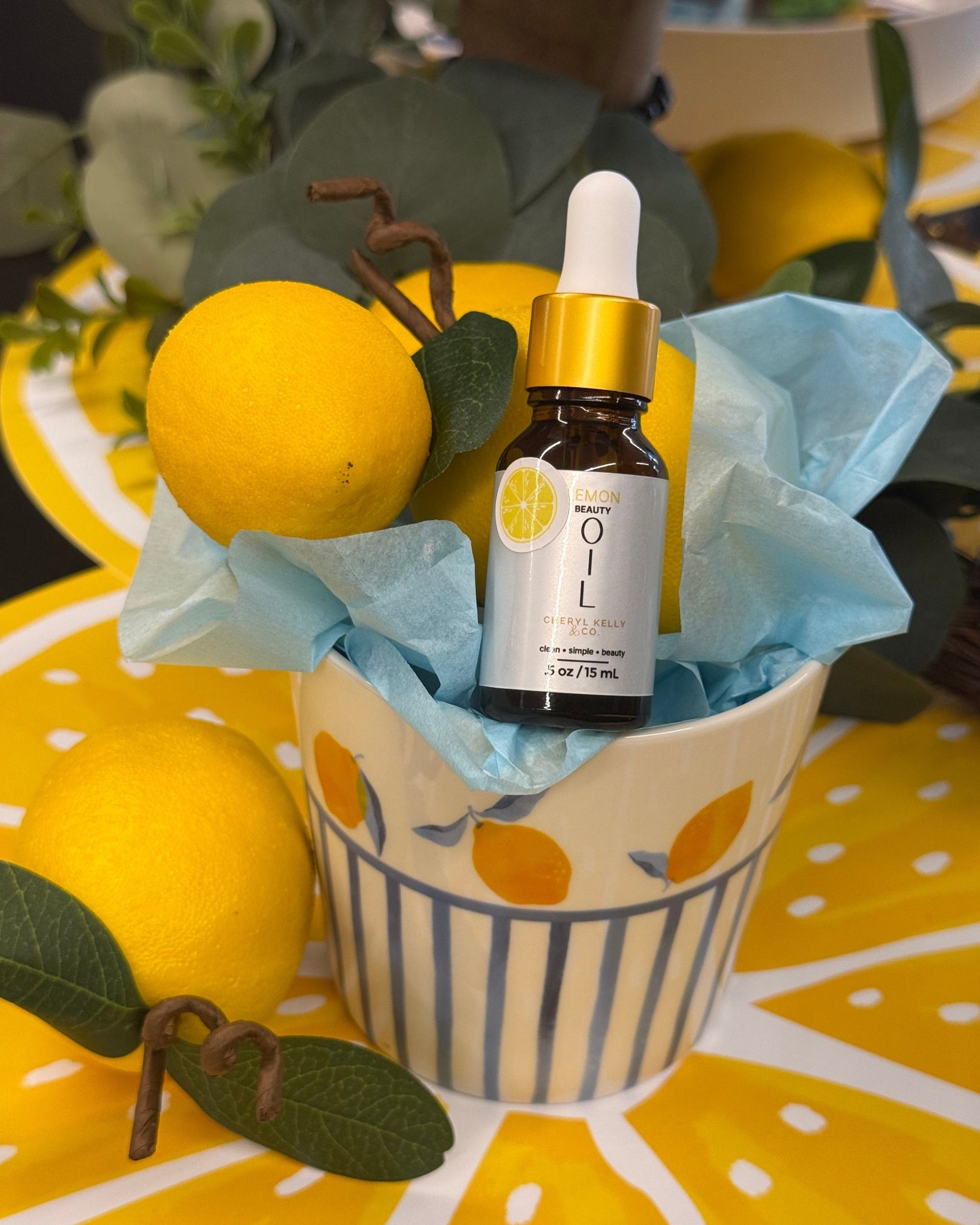 Lemon Beauty Oil Summer Edition by Cheryl Kelly & Co. surrounded by lemons.