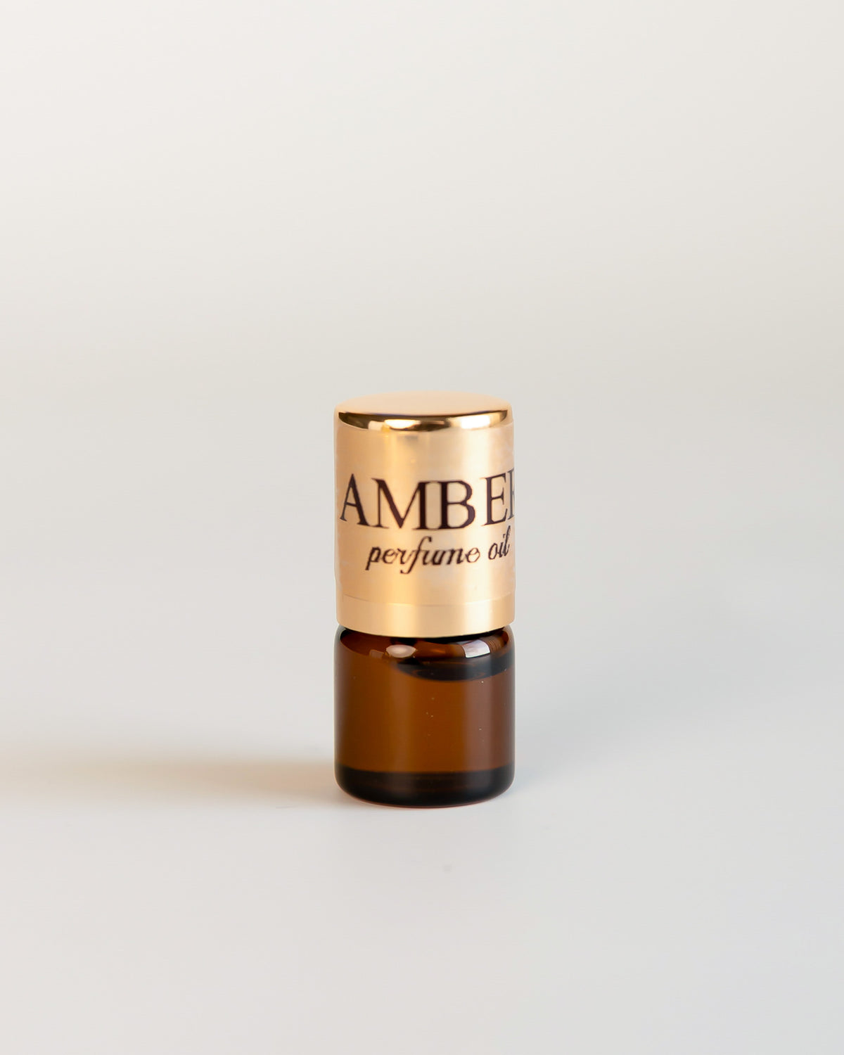 CKCo AMBER No1 perfume oil in a 1 mL sample vial with a gold label on a light neutral background.