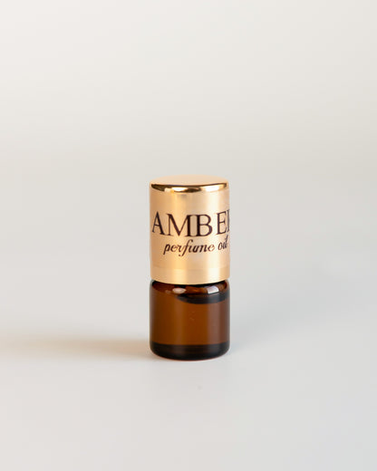 CKCo AMBER No1 perfume oil in a 1 mL sample vial with a gold label on a light neutral background.