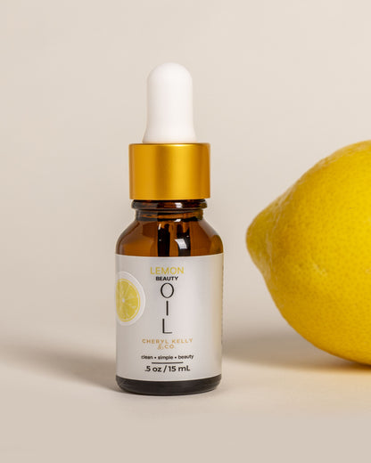 Cheryl Kelly &amp; Co. Lemon Beauty Oil Summer Edition clean facial oil next to fresh lemon on white background